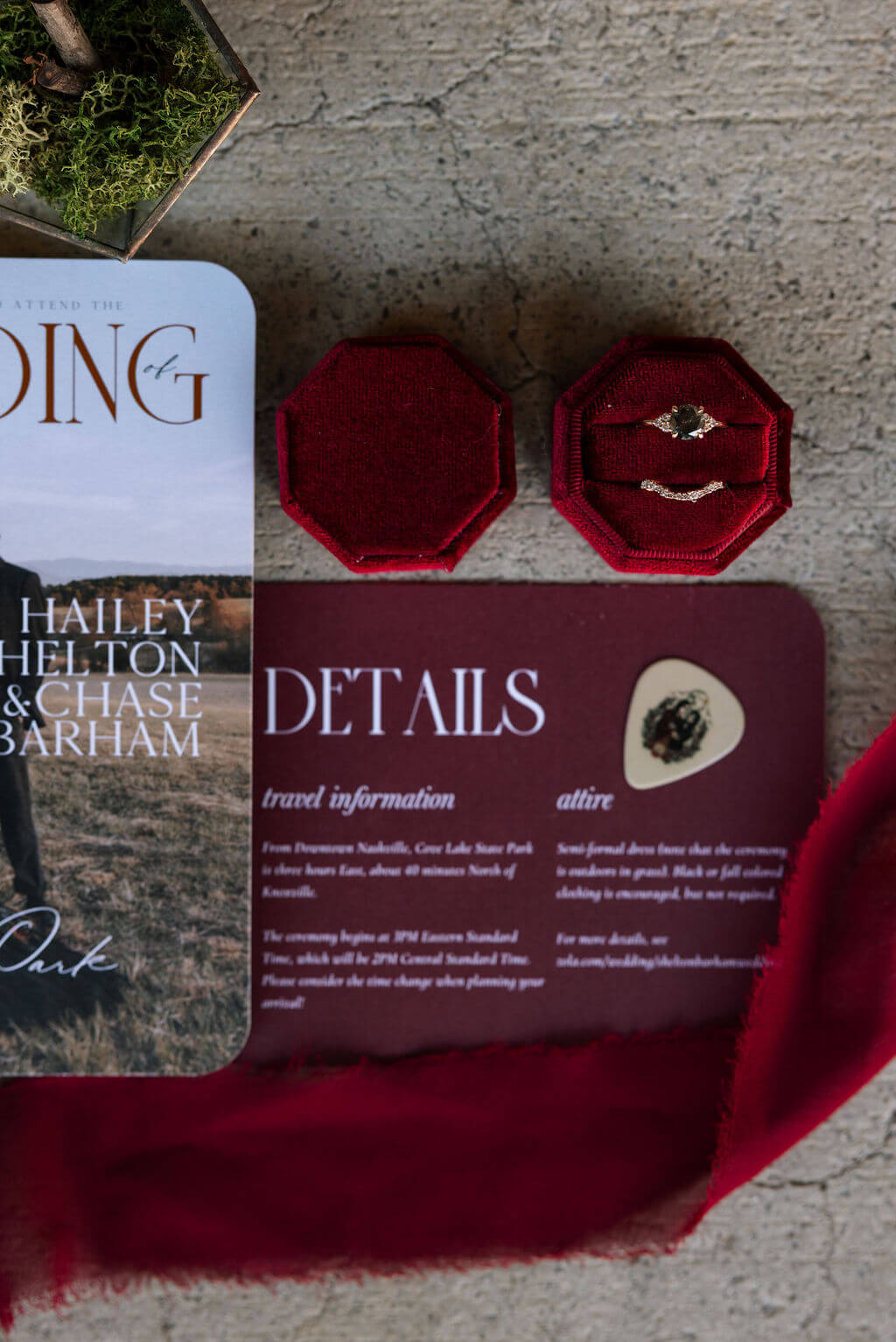 Burgundy wedding invitation suite styled with wedding rings, greenery, and geometric glass details.