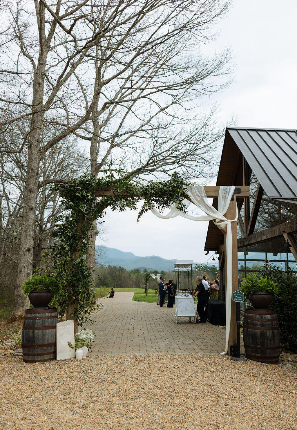 Entrance to a rustic East Tennessee wedding venue with wooden buildings, draped decor, and mountain views beyond the property.