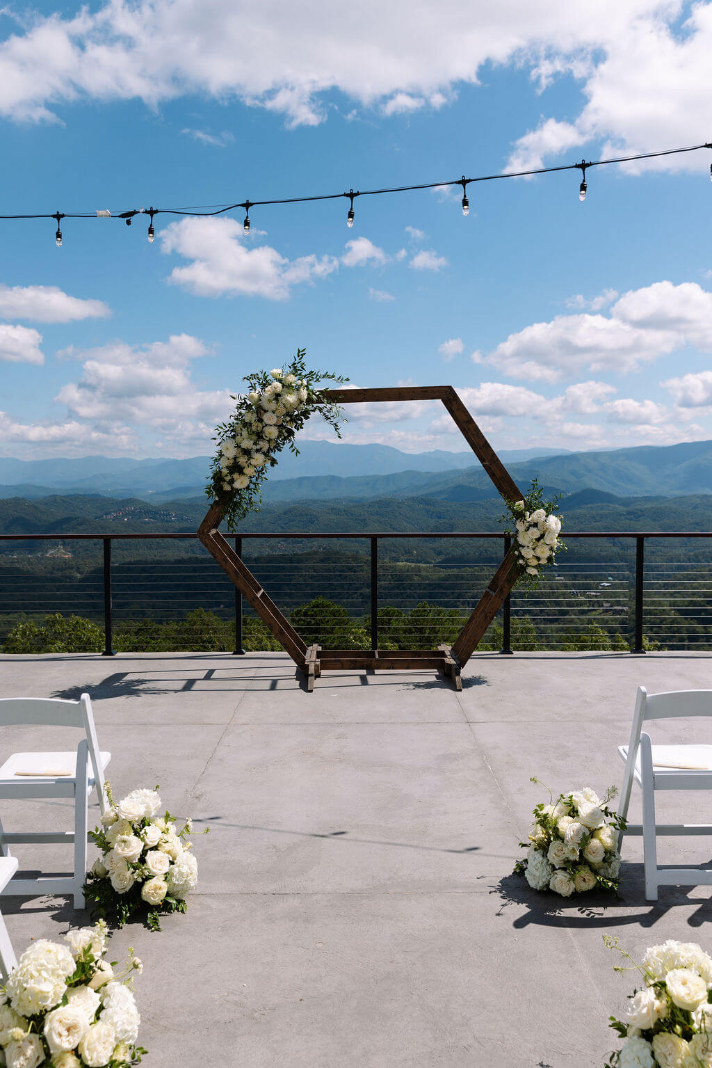 Outdoor wedding ceremony setup with a wooden hexagon arch, white flowers, and mountain views in East Tennessee.