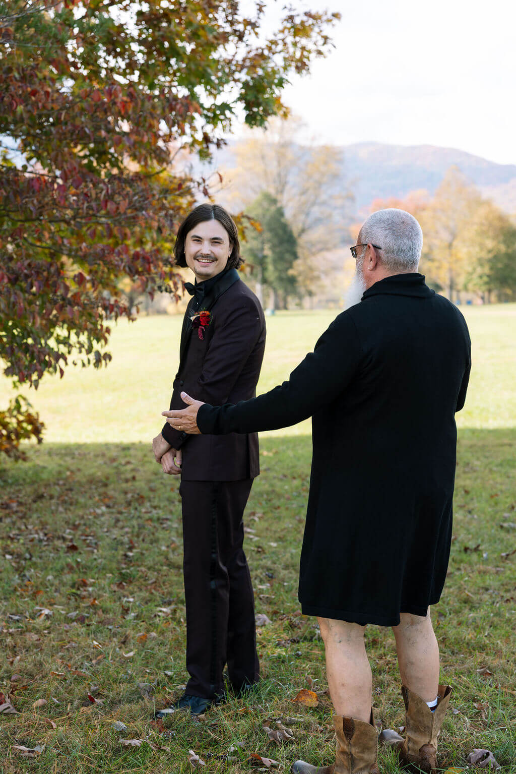 The groom turns around smiling as the bride’s uncle surprises him during a playful fake first look.