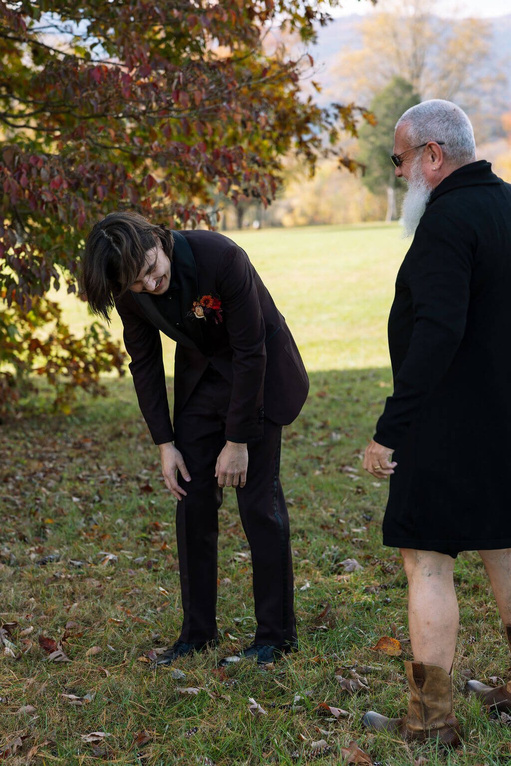 The groom bends over laughing with the bride’s uncle after their funny fake first look prank.