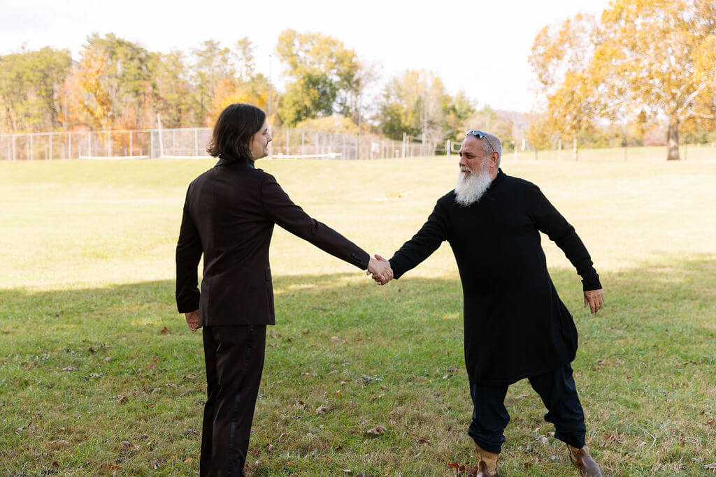 Groom and bride's uncle shake hands while laughing