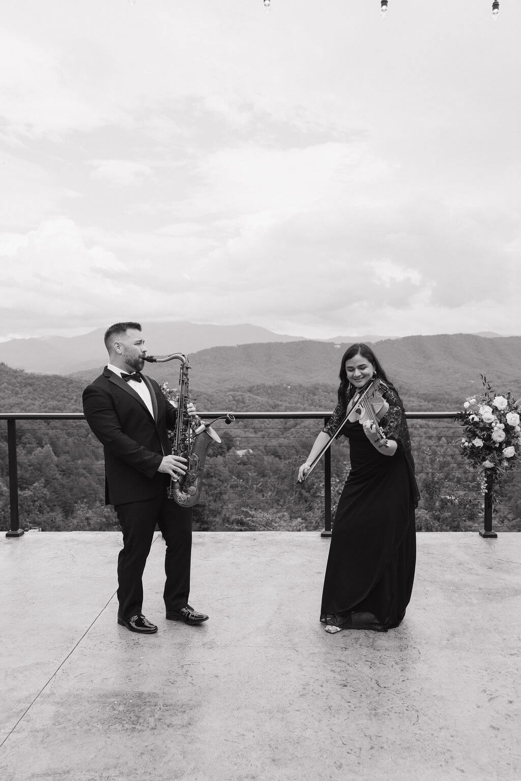Violinist and musician performing outdoors with sweeping mountain views behind them before the wedding ceremony.