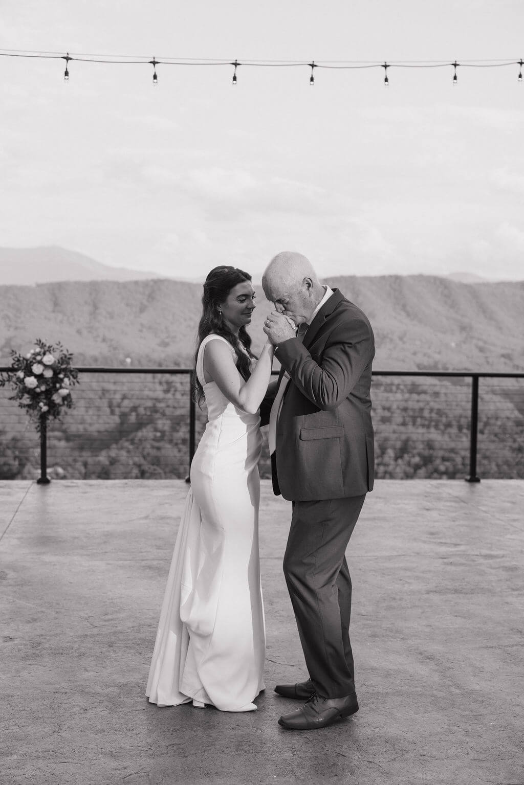 Black-and-white photo of the bride dancing with an older man as he becomes emotional during the reception.