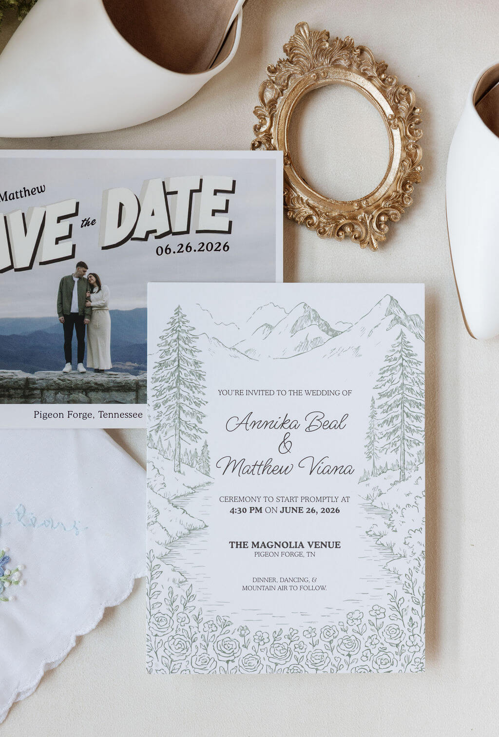 Flat lay of wedding stationery, a save-the-date card, invitation suite, and vintage gold frame.