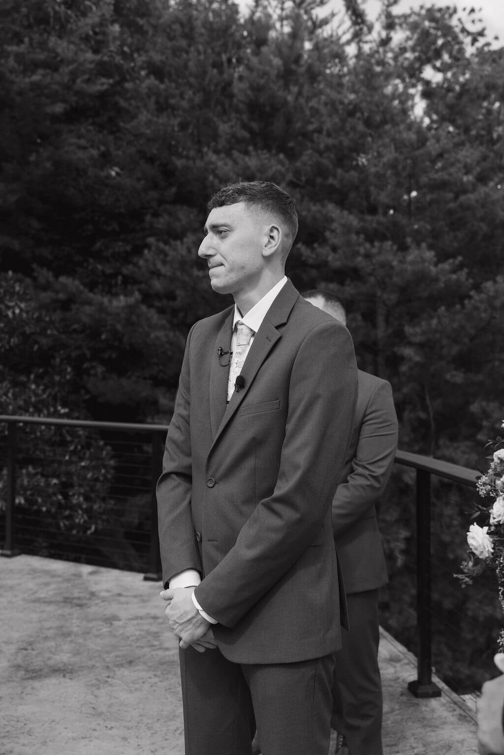 Black-and-white portrait of the groom waiting at the ceremony before the bride walks down the aisle.