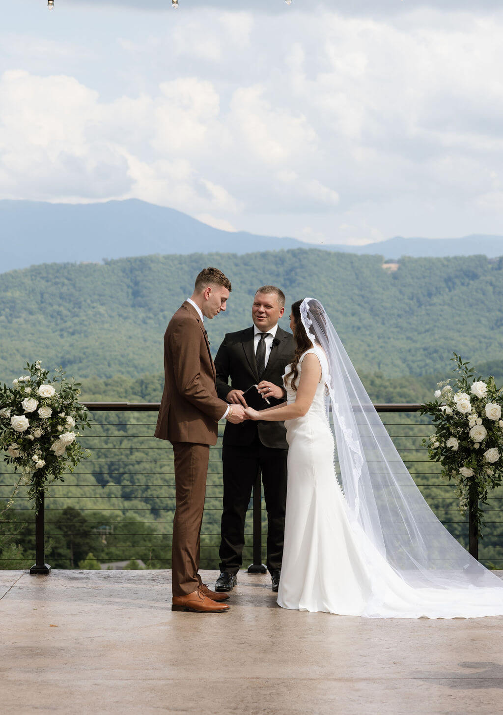Bride and groom standing together at the altar during their outdoor ceremony with the officiant and mountains behind them.