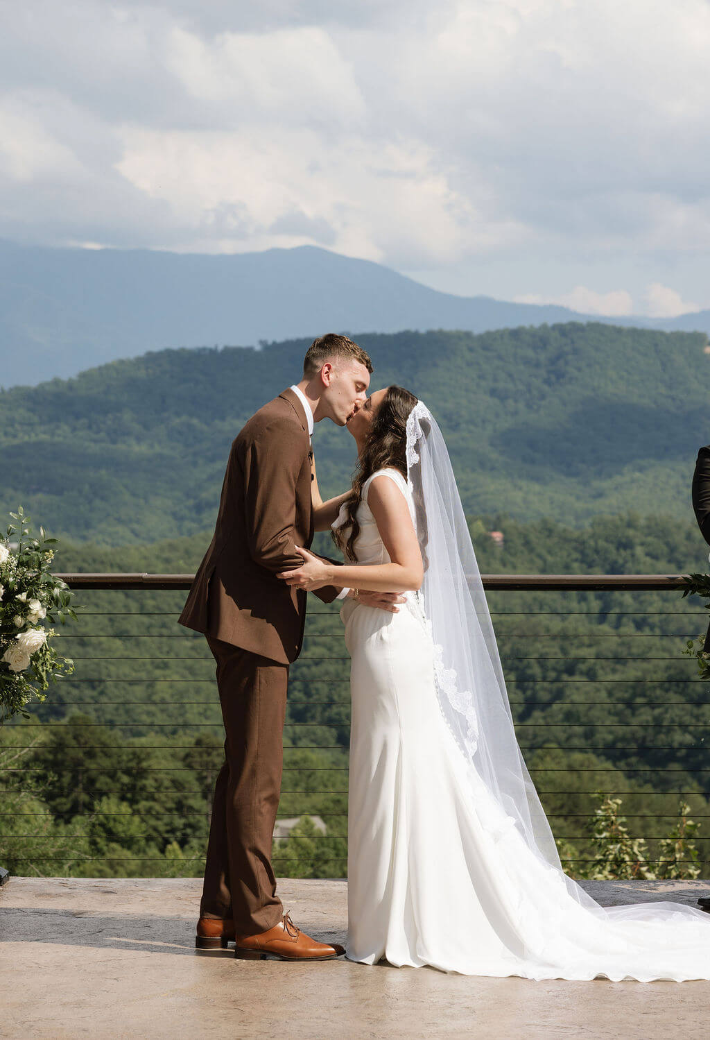 Bride and groom kissing at the altar during their outdoor mountain wedding ceremony.