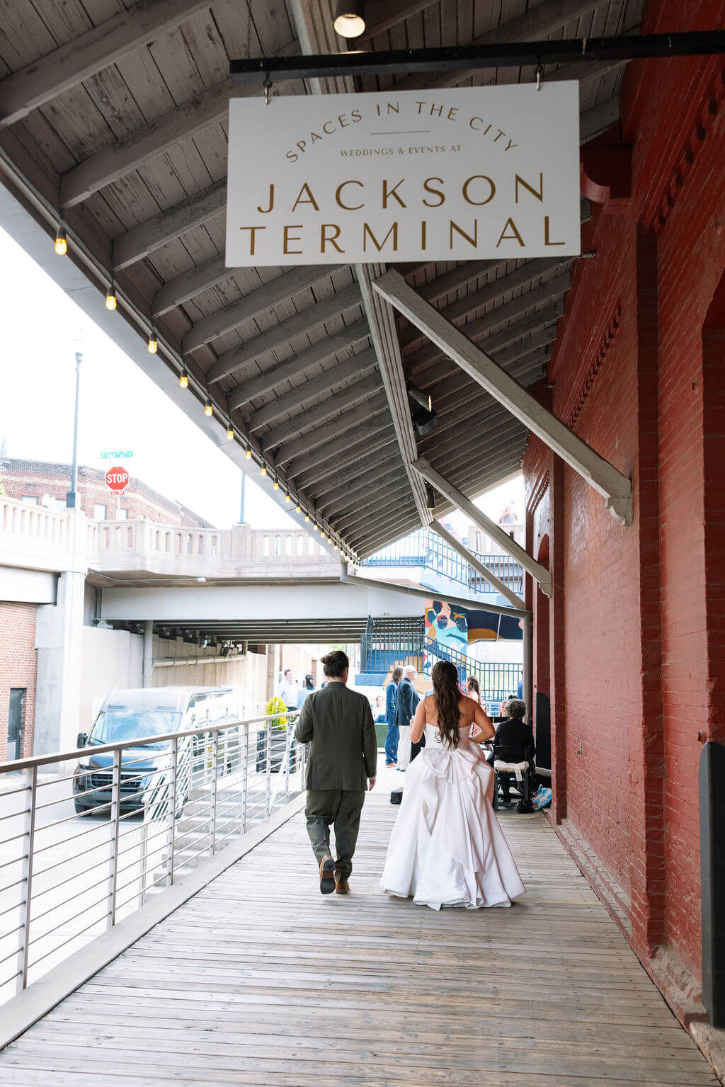 Bride and groom walking away beneath the Jackson Terminal sign along the covered wooden platform