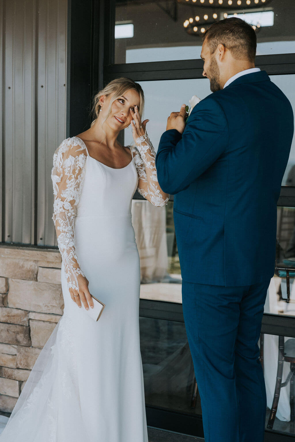 Bride wiping away tears as the groom reaches toward her during an emotional wedding-day moment.