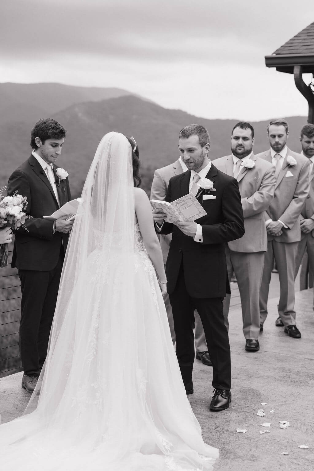 Black-and-white photo of the bride and groom exchanging vows during their mountain-view ceremony.