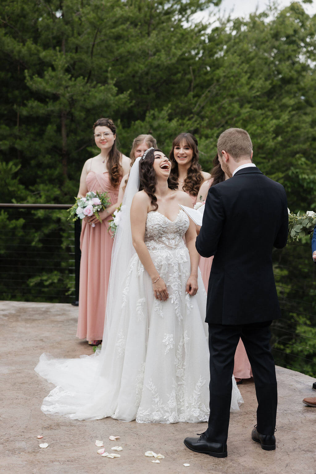 Bride laughing during the wedding ceremony while standing across from the groom.