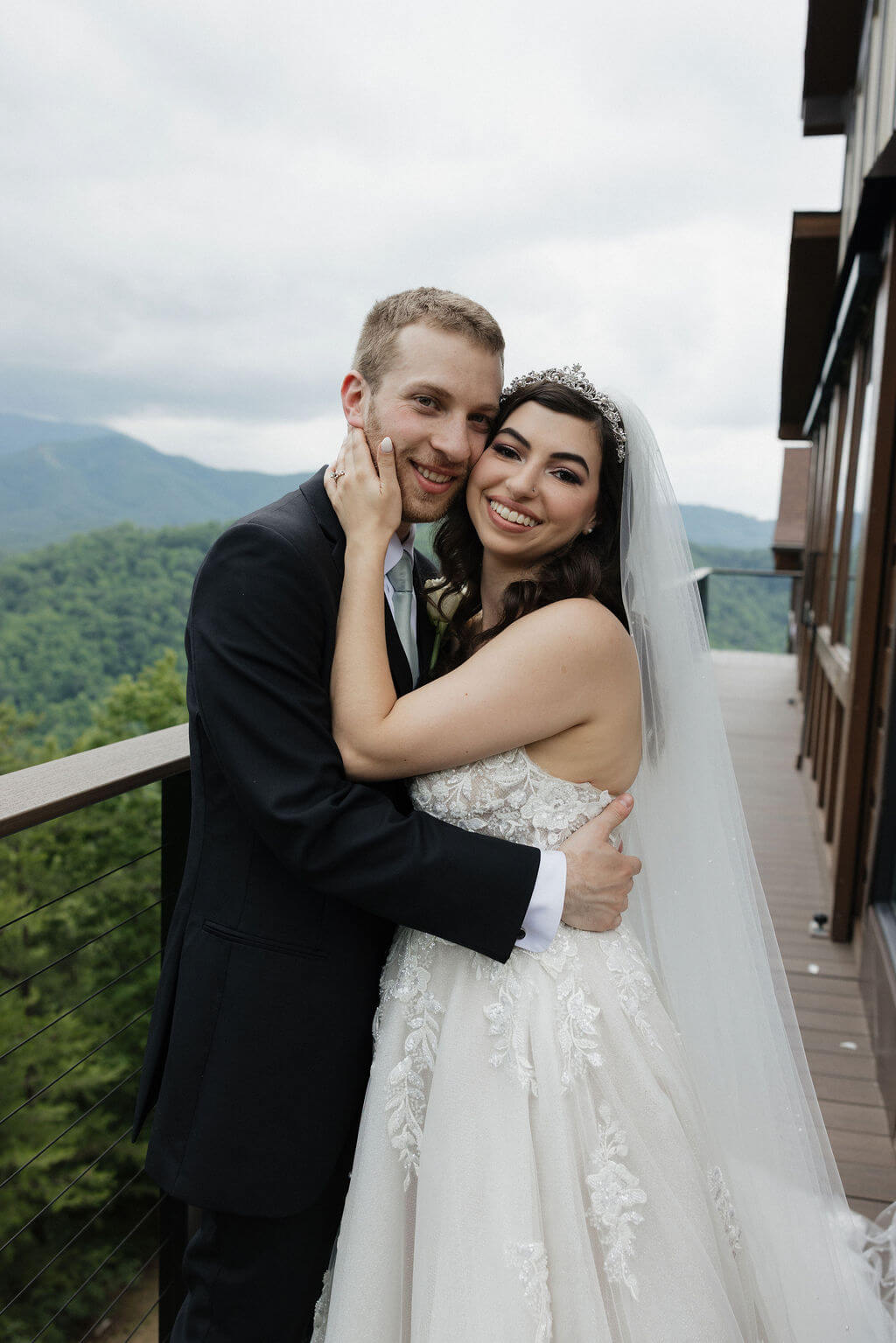 Bride and groom embracing on the balcony at The Magnolia with mountain scenery in the background.