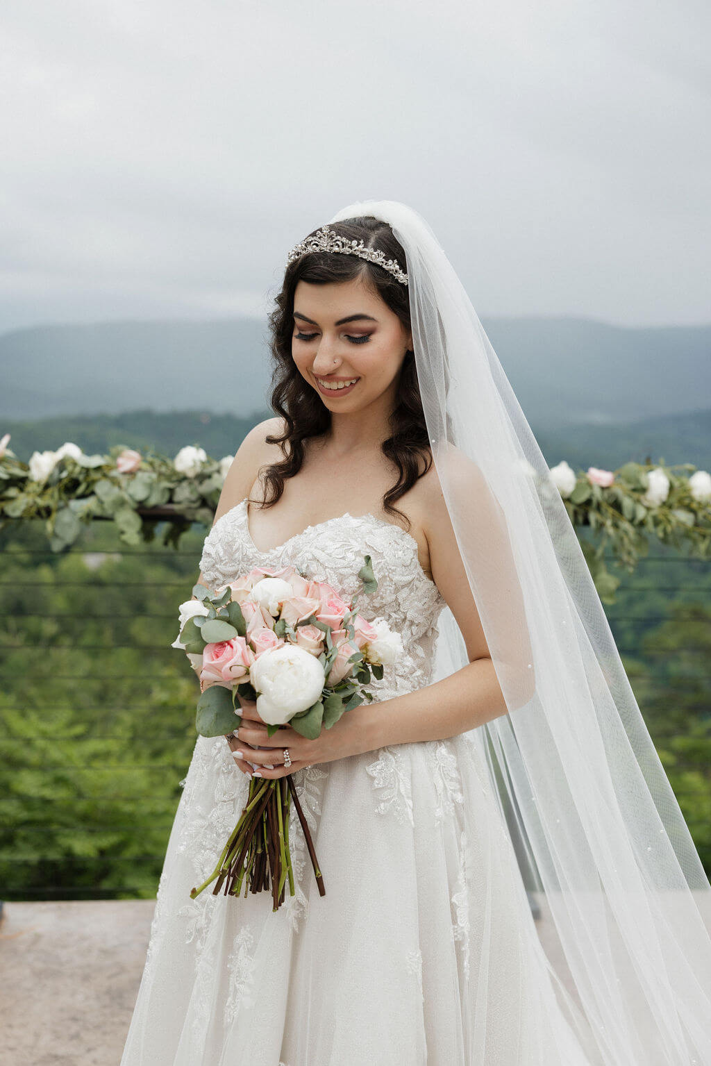 Bridal portrait with the bride holding a pink and white bouquet against a Smoky Mountain backdrop.