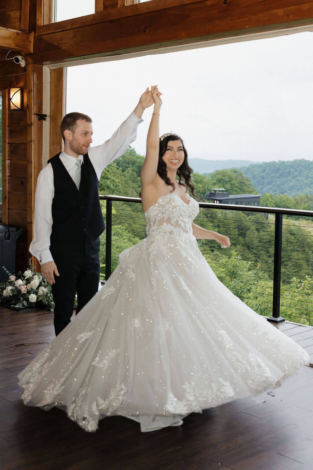 Bride twirling in her wedding dress with the groom on a balcony overlooking the Smoky Mountains.