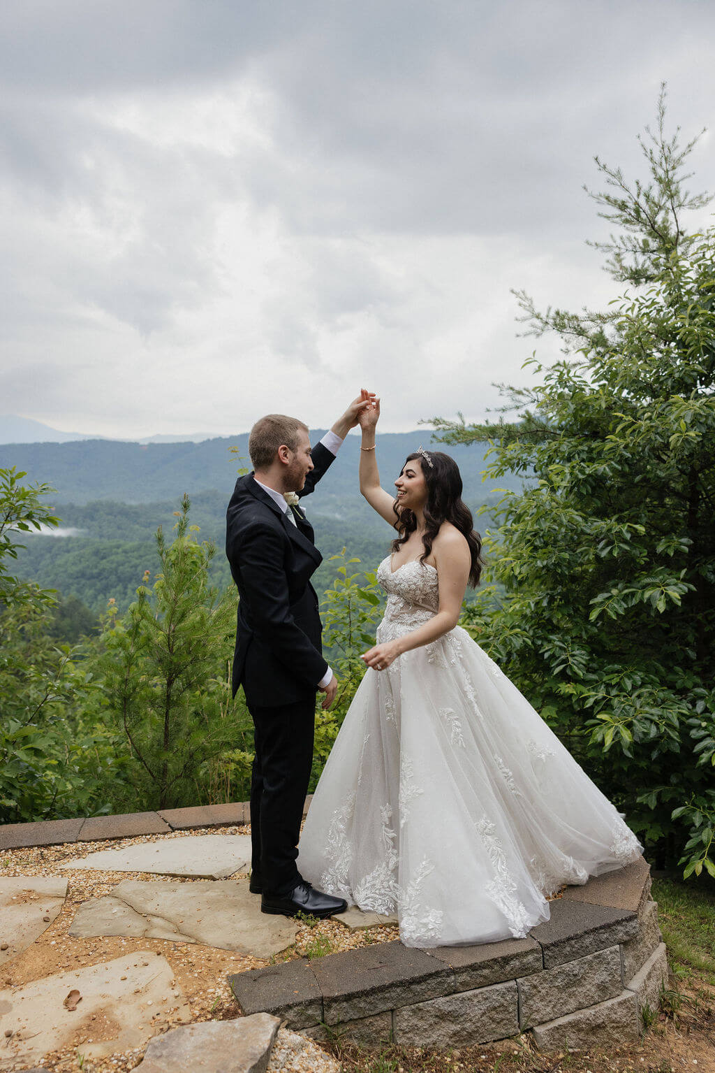 Groom twirling the bride on a stone overlook surrounded by Smoky Mountain views.