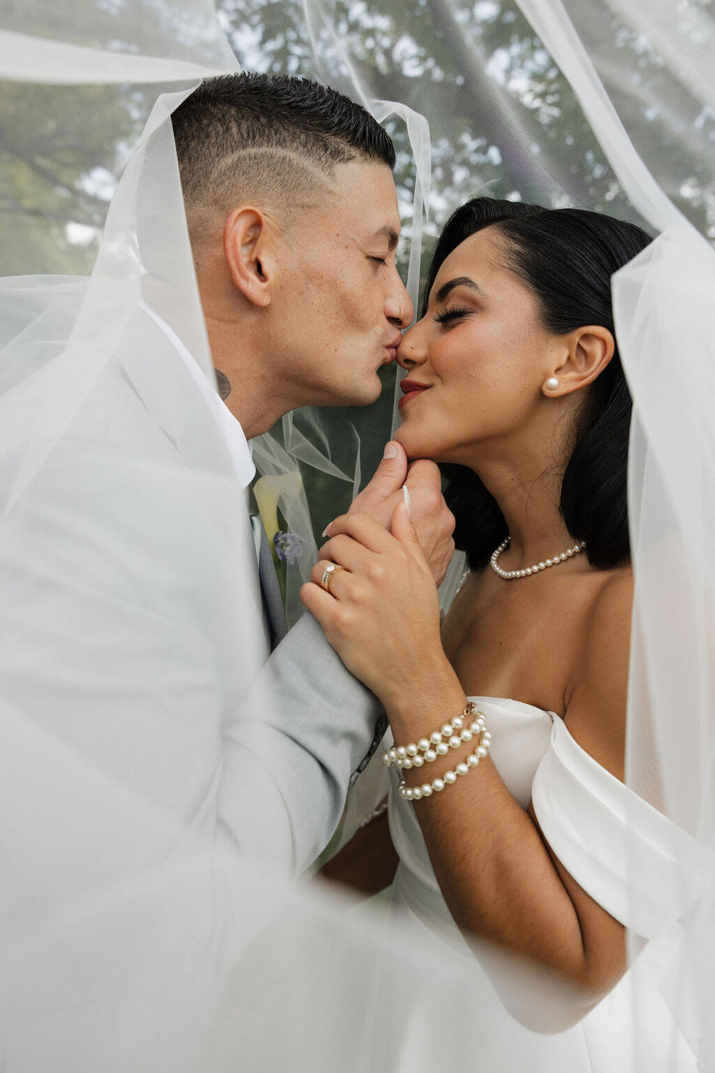 Close-up of the bride and groom kissing beneath her flowing veil.