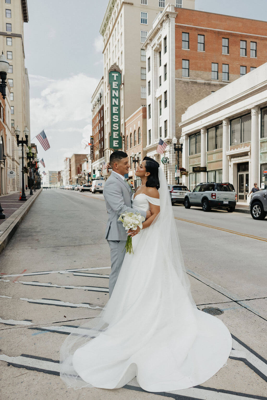 Bride and groom posing on a downtown Knoxville street with the Tennessee Theatre sign behind them.