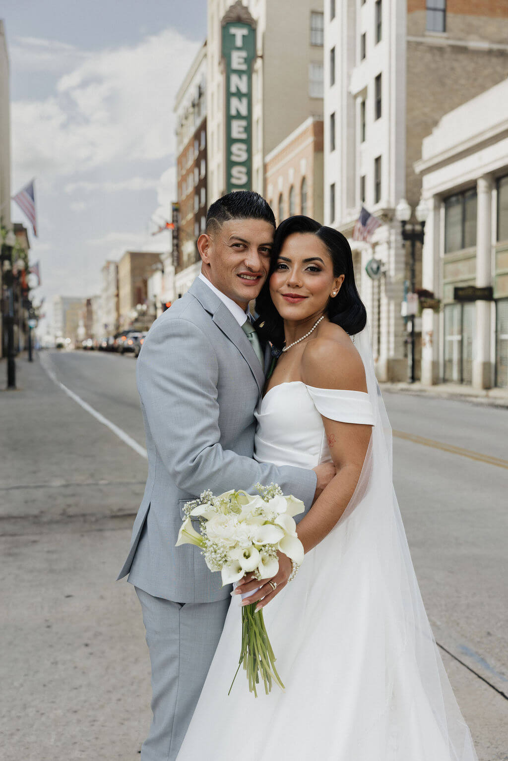 Bride and groom posing together on a downtown Knoxville street with the Tennessee Theatre sign in the background.