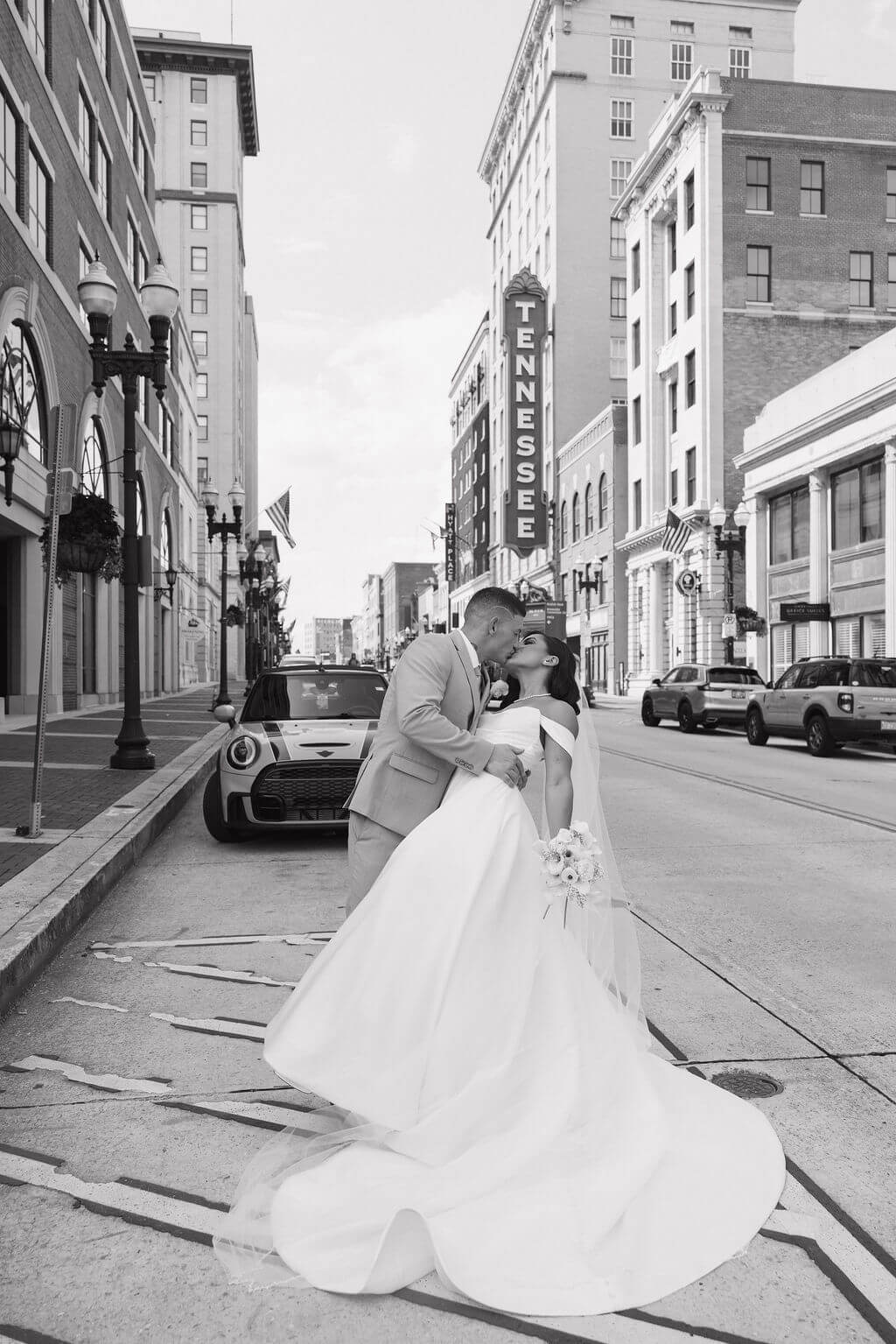 Black-and-white photo of the groom dipping and kissing the bride during portraits in downtown Knoxville.