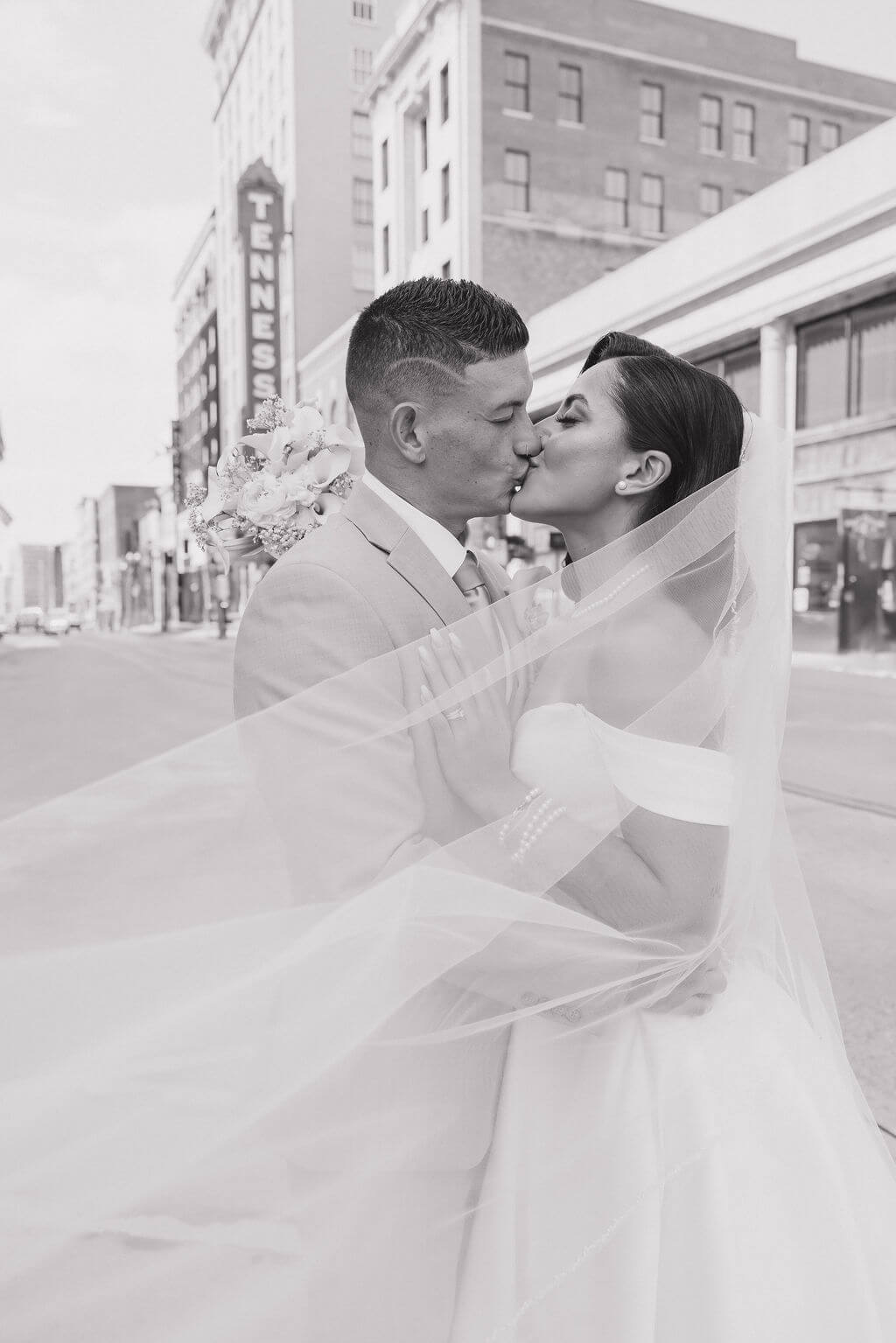 Black-and-white photo of the bride and groom kissing beneath her veil during portraits near The Mill and Mine.