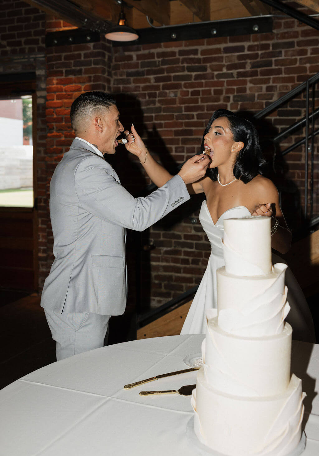 Groom feeding the bride a bite of wedding cake during their reception at The Mill and Mine.