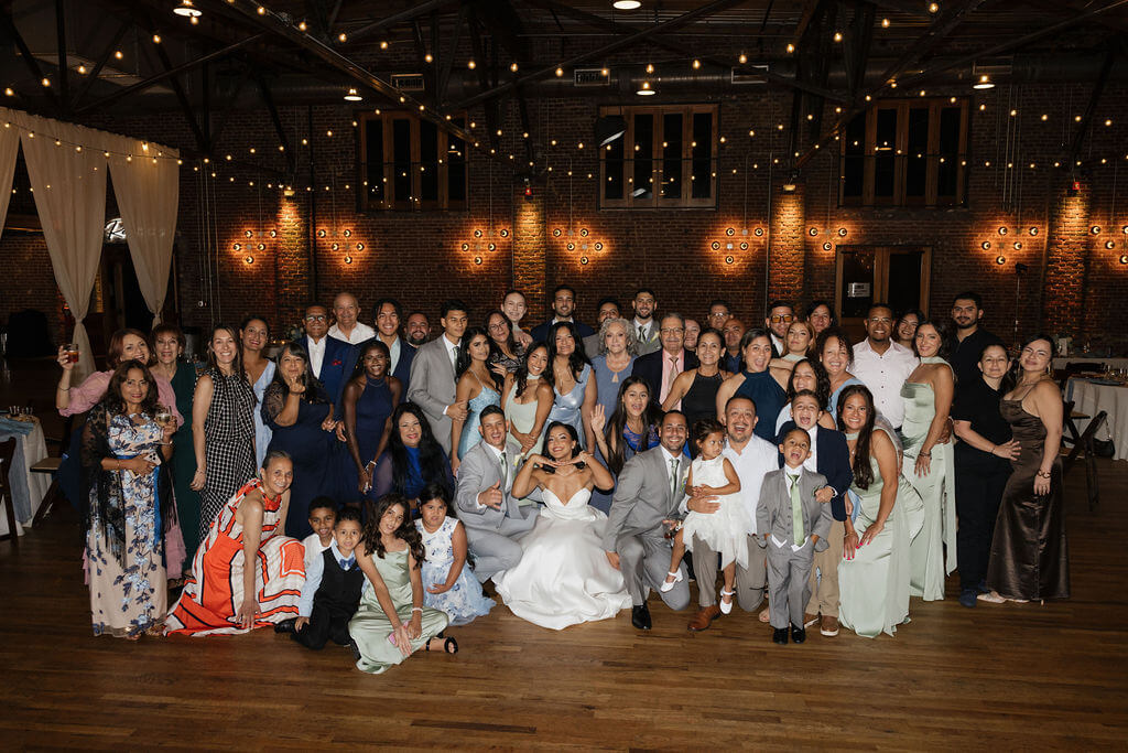 Bride and groom surrounded by family and friends for a large group photo inside The Mill and Mine reception space.