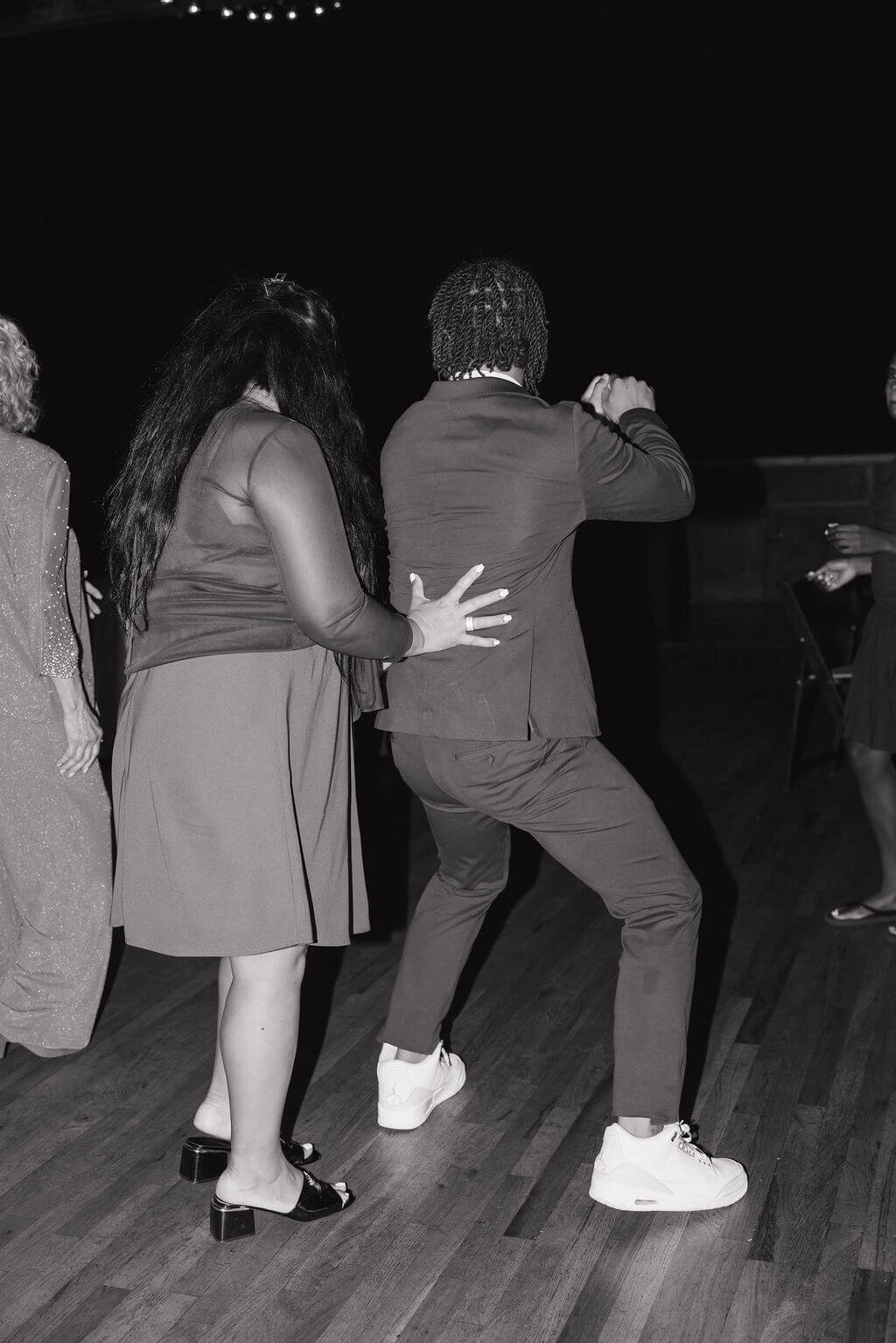 Black-and-white candid of wedding guests dancing together during the reception.