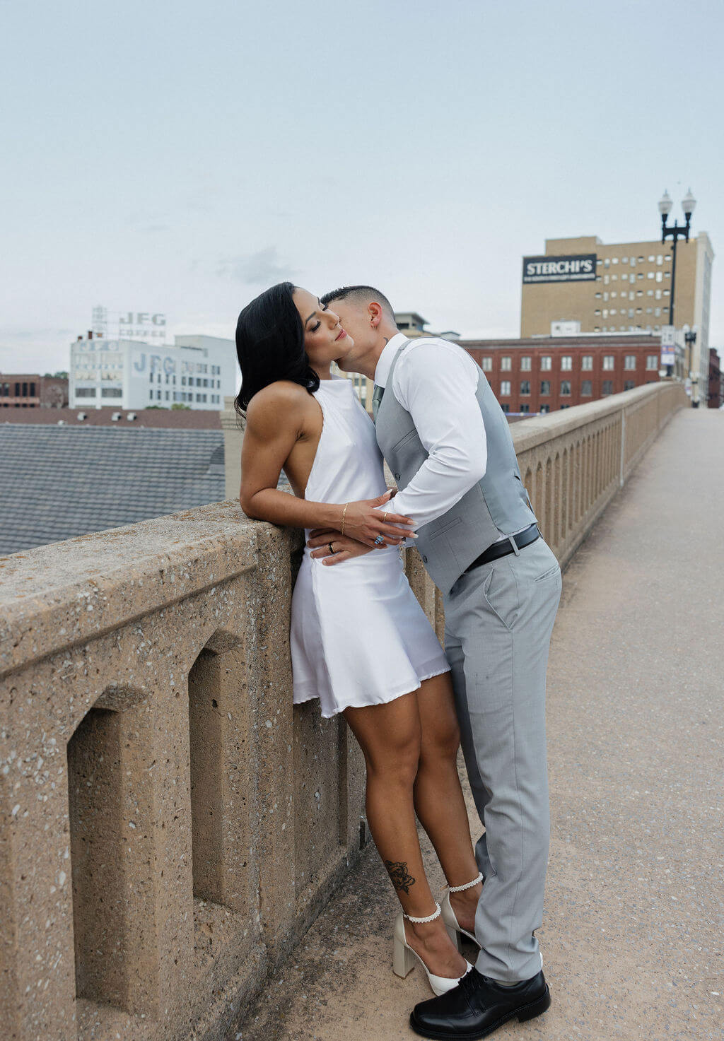 Bride and groom kissing beside a concrete railing during downtown Knoxville wedding portraits.