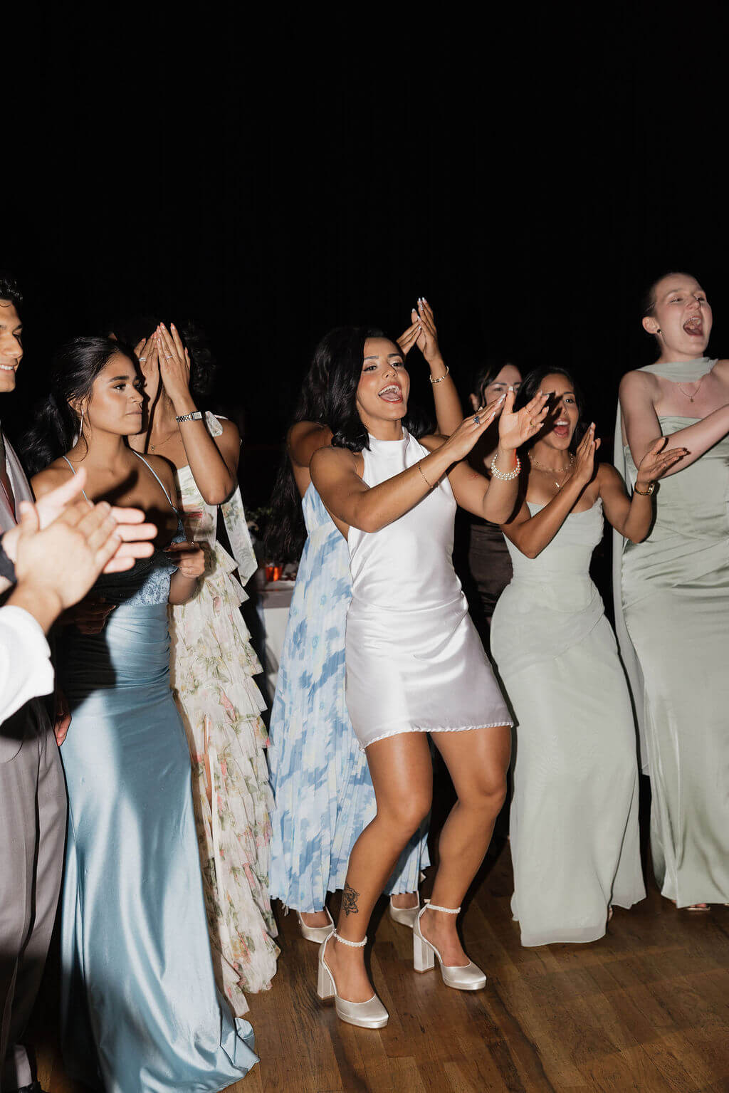 Bride in a short white reception dress dancing with friends on the dance floor at The Mill and Mine.
