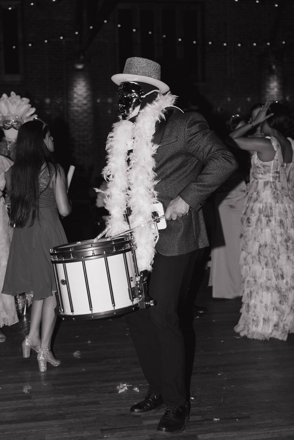 Black-and-white candid of a costumed drummer performing during the Hora Loca at The Mill and Mine wedding reception.