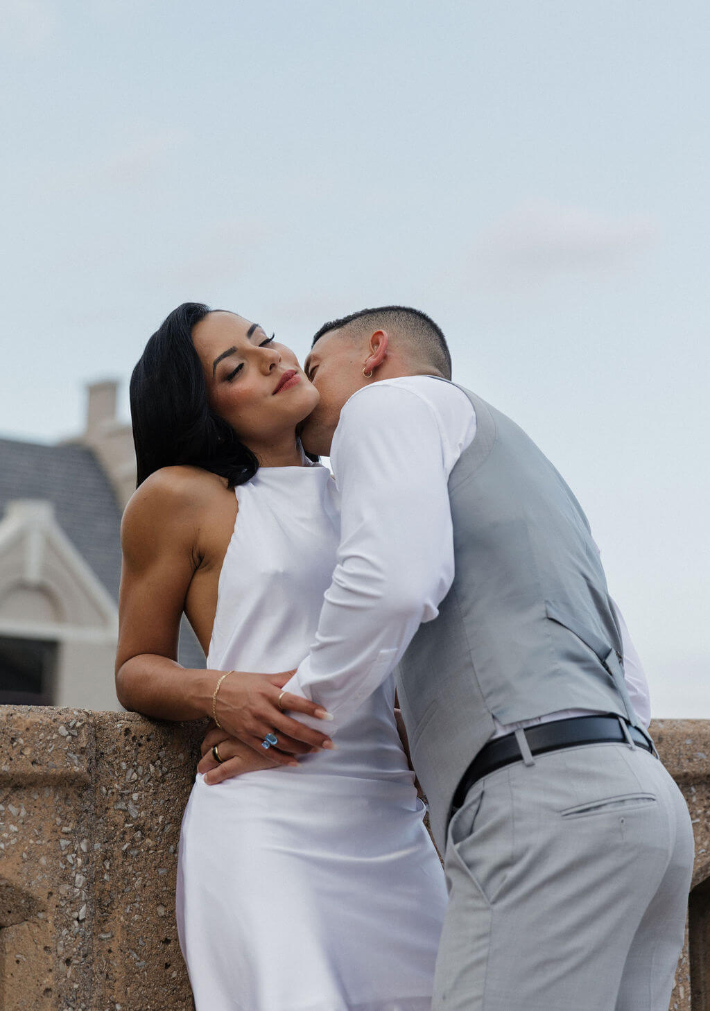 Bride and groom embracing beside a concrete railing during their downtown Knoxville wedding portraits.