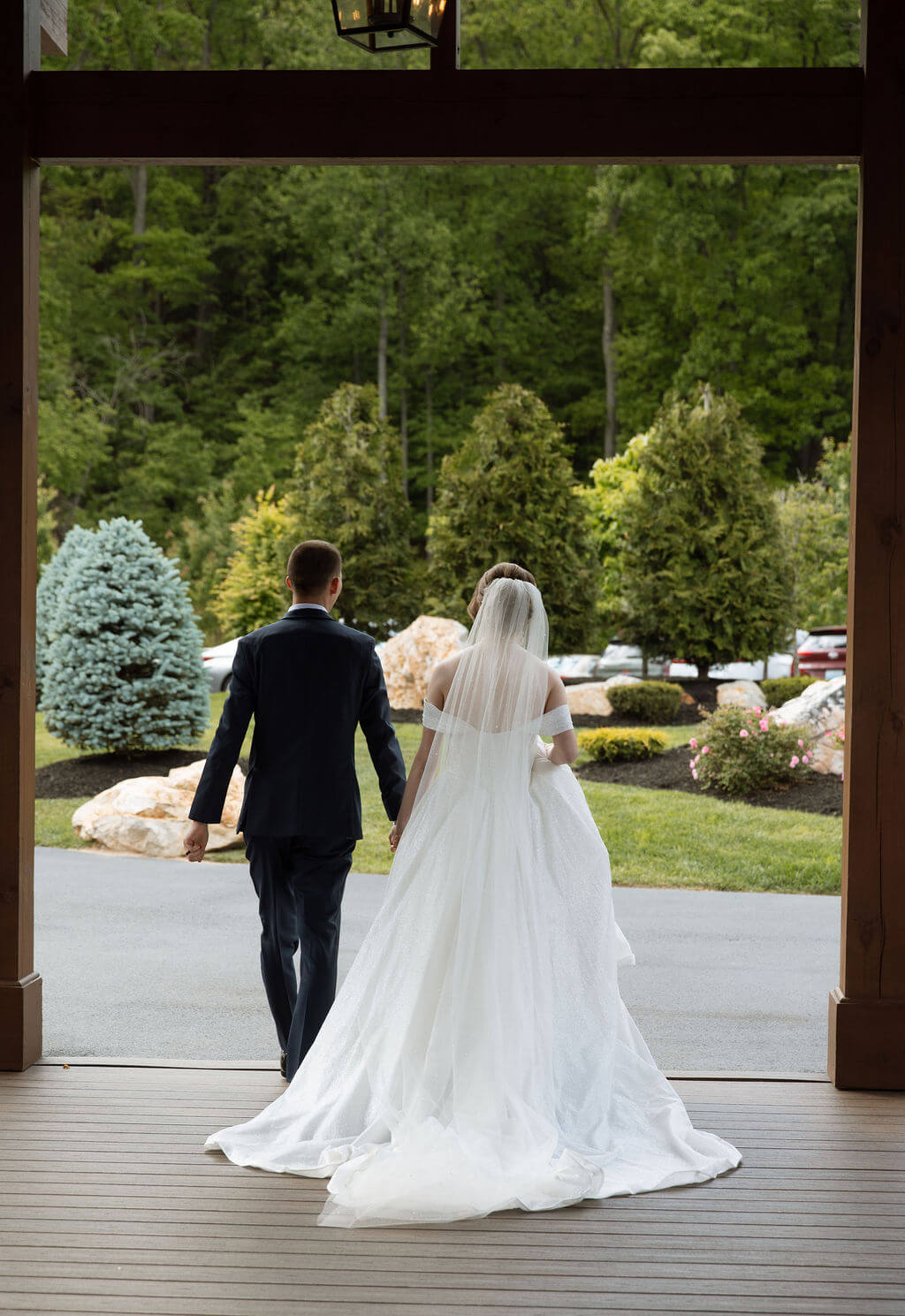 Bride and groom walk hand in hand through the covered entrance of their wedding venue.