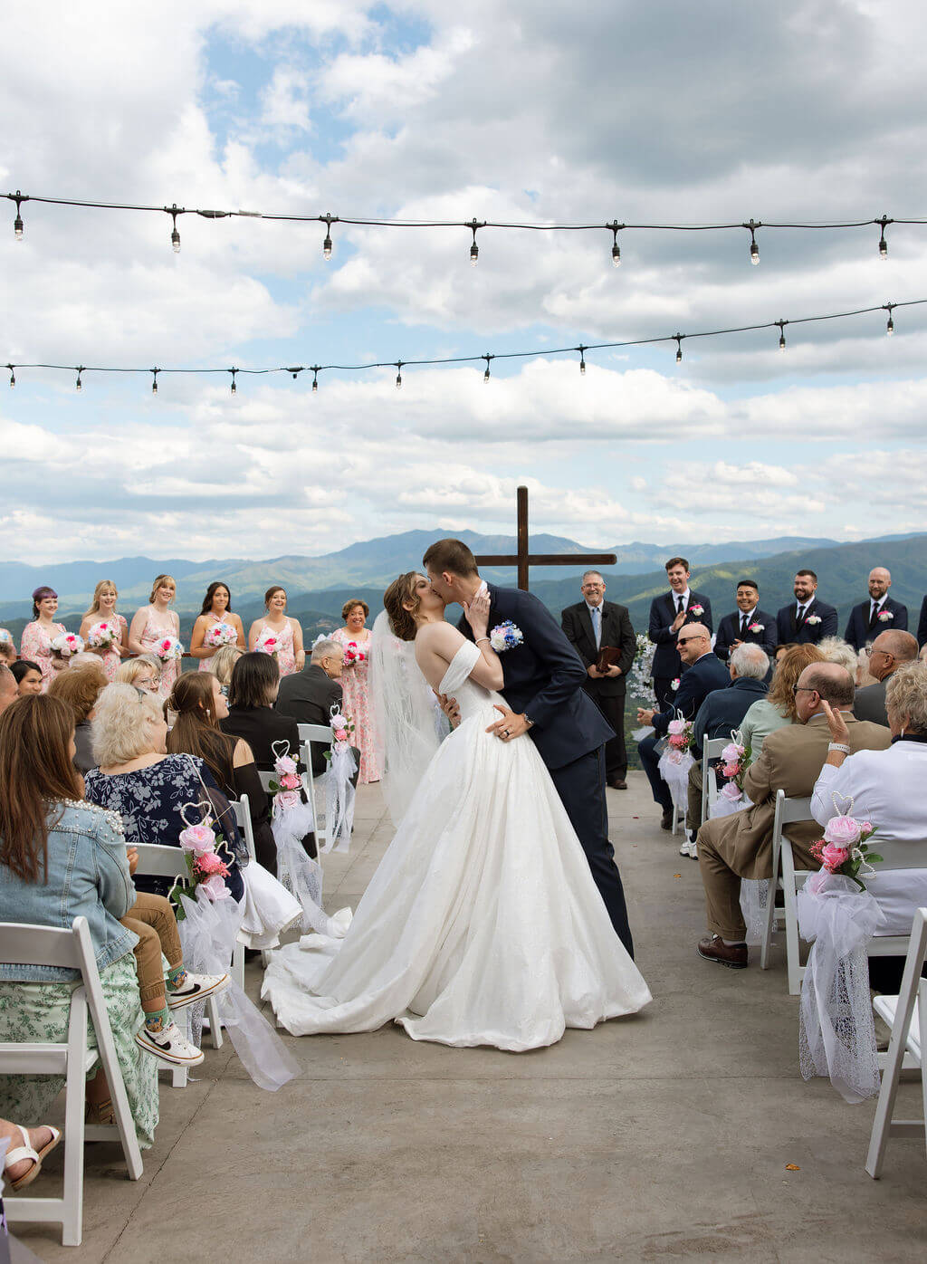 Bride and groom share a kiss at the end of the aisle during an outdoor mountain wedding ceremony.