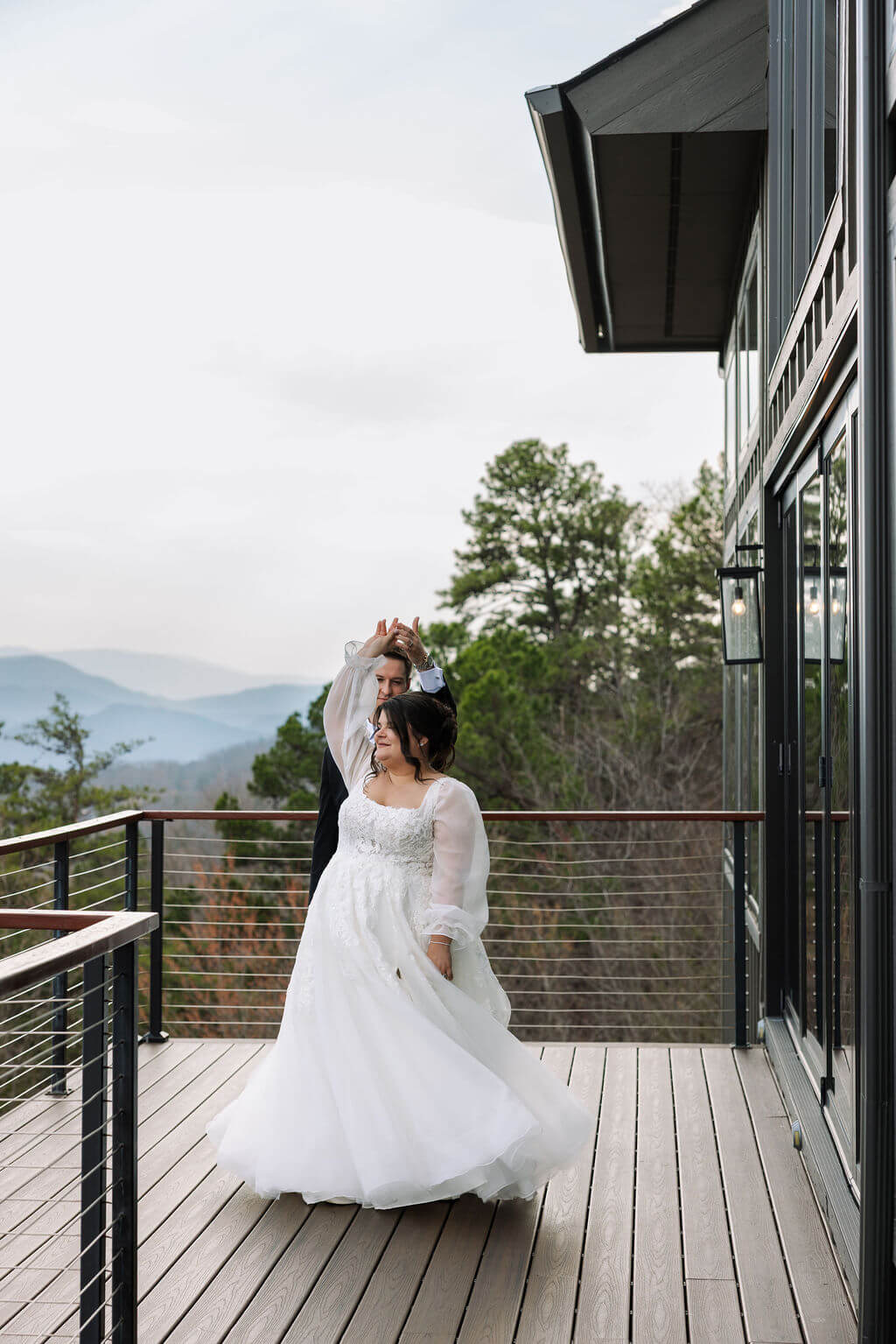 Bride twirls in her wedding dress on a wooden balcony overlooking the Smoky Mountains.