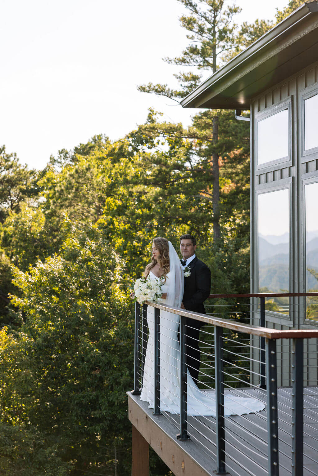 Bride and groom embrace on a narrow balcony outside their mountain wedding venue.