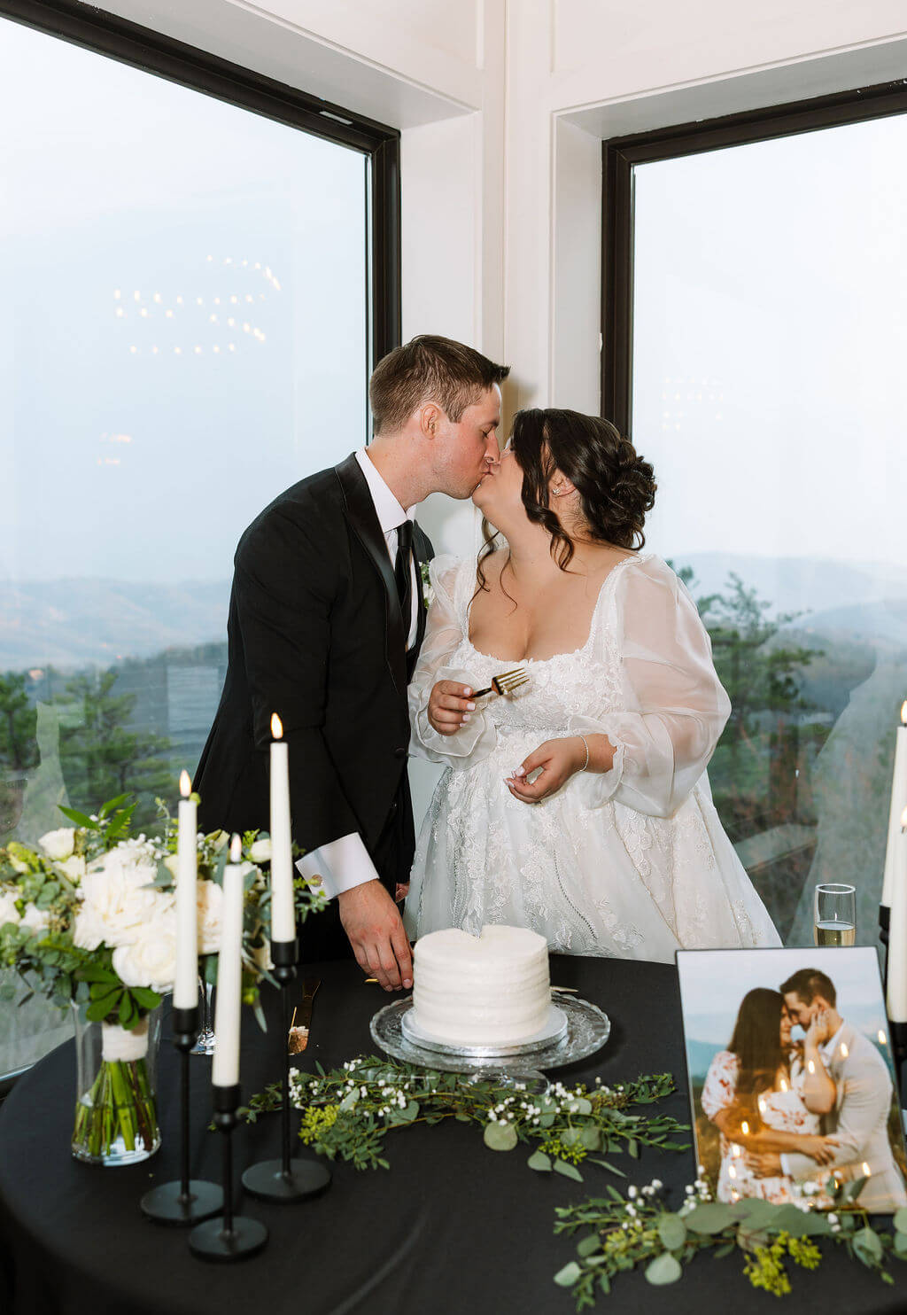 Bride and groom kiss after cutting their wedding cake
